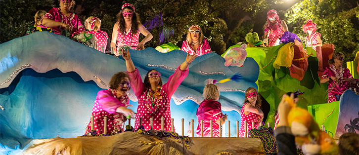 women on a mardi gras float dressed in pink polka dot outfits